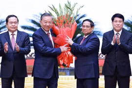 Le Premier ministre Pham Minh Chinh (2e à partir de la droite) offre des fleurs à To Lam (2e à partir de la gauche) après son élection au poste de secrétaire général du Comité central du Parti du 13e mandat. Photo: VNA