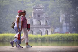 Les touristes étrangers se promènent au bord du lac Hoan Kiem. Photo : VNA
