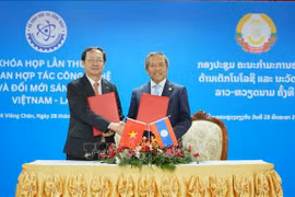 Le ministre vietnamien de la Science et de la Technologie Huynh Thanh Dat (à gauche) et le ministre lao des Technologies et de la Communication Boviengkham Vongdara échangent le procès-verbal de la première session. Photo: VNA