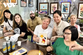 En visitant l'atelier Vun Art, les touristes étrangers peuvent expérimenter la réalisation de peintures sur tissus avec l’aide des artisans handicapés de l’atelier. Photo: VOV