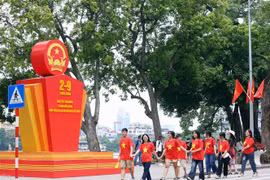 Des jeunes marchent en liesse devant un paneau célébrant la 79e Fête nationale du Vietnam, près du lac Hoàn Kiêm, à Hanoi. Photo : VNA