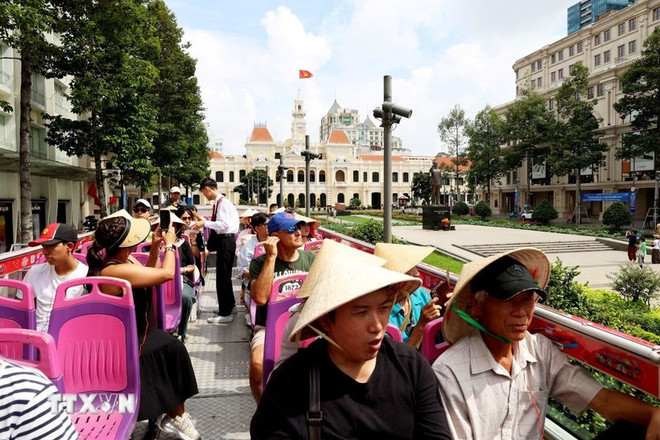 Les touristes internationaux visitent le centre-ville d'Ho Chi Minh-Ville en bus à impériale. Photo : VNA 2-9313.jpg
