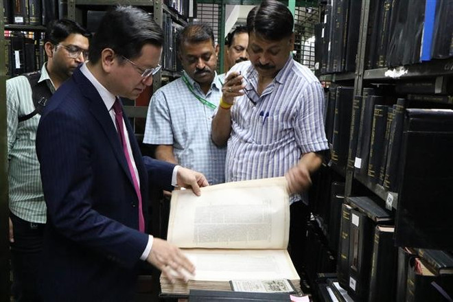 L'ambassadeur Nguyen Thanh Hai lit l'un des livres les plus anciens de la collection de livres rares de la bibliothèque. Photo : VNA sach.jpg