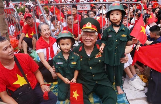 Un vétéran et ses enfants arrivent tôt à l'intersection Hung Vuong-Tran Phu pour assister à la deuxième répétition générale du défilé. Photo : Van Diep - VNA 2.jpg