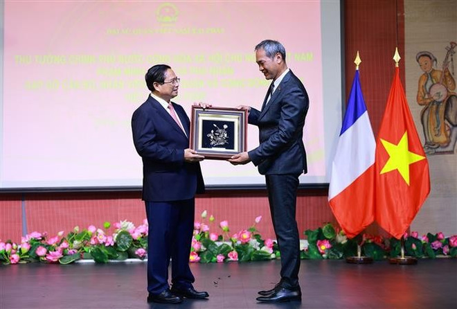 Le Premier ministre Pham Minh Chinh offre un cadeau à un représentant de la communauté vietnamienne en France. Photo : VNA tang-qua.jpg