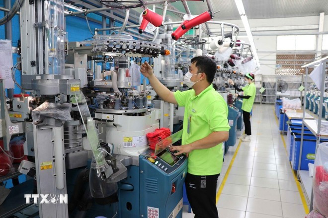 Un ouvrier de l'usine Sung Hwa Vina (capitale sud-oréenne) dans le parc industriel de Hoa Binh (Tay Ninh) vérifie le fil sur une machine à tisser des chaussettes. Photo :VNA 3.jpg