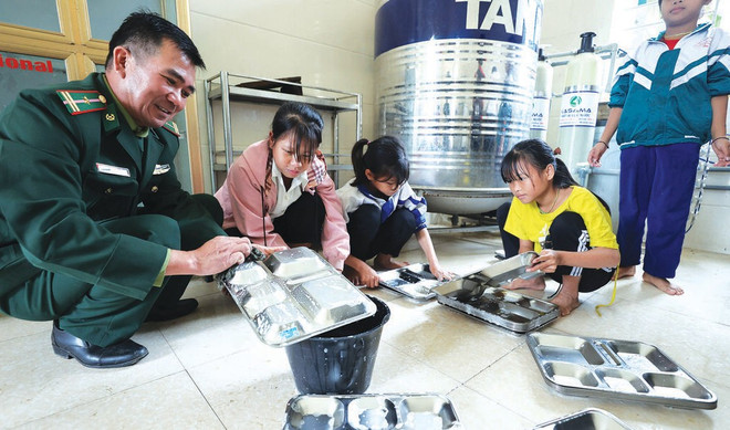 Un garde-frontière du poste de Môn Son apprend aux élèves à nettoyer correctement leurs plateaux. Photo : CVN nghe-an-3.jpg
