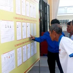 Des électeurs issus des minorités ethniques de la commune de Bắc Bình (Lâm Dông) consultent les biographies des candidats avant le jour du scrutin. Photo : VNA