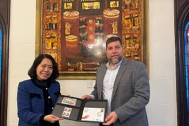 Le député Victor Aldaya remet à l'ambassadrice Ngô Minh Nguyêt une série de timbres commémorant le 20e anniversaire des relations diplomatiques entre le Vietnam et l'Uruguay, avec un portrait du général Vo Nguyên Giap. Photo: VNA