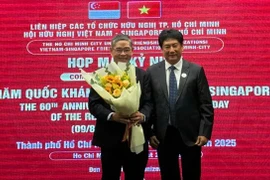 Le président de l'Association d'amitié Vietnam - Singapour (gauche) offre un bouquet de fleurs au consul général de Singapour à Hô Chi Minh-Ville, Pang Te Cheng. Photo: sggp