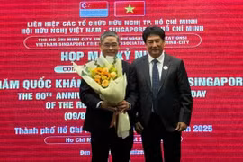 Le président de l'Association d'amitié Vietnam - Singapour (gauche) offre un bouquet de fleurs au consul général de Singapour à Hô Chi Minh-Ville, Pang Te Cheng. Photo: sggp