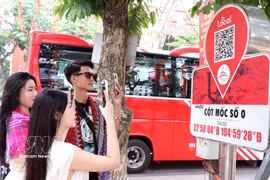Les touristes scannent le code QR au km 0 à Ha Giang pour obtenir des informations touristiques. Photo: VNA