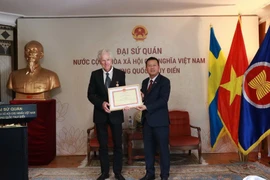 L’ambassadeur du Vietnam en Suède, Trân Van Tuân (droite), remet l’insigne « Pour la cause de la Culture, des Sports et du Tourisme » au réalisateur suédois Bo Öhlén. Photo: VNA
