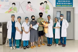 Le personnel médical de l'hôpital offre des fleurs au couple et à leur bébé pour les féliciter de leur sortie de l'hôpital. Photo : VNA