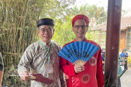 Des diplomates étrangers vêtus de l’ao dai traditionnel vietnamien lors de l'événement. Photo: VNA