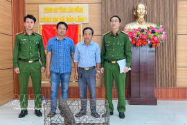 Doan Hong Hai (troisième à partir de gauche) remet un pangolin rare aux autorités de la commune de Bao Lam 1. Photo : VNA
