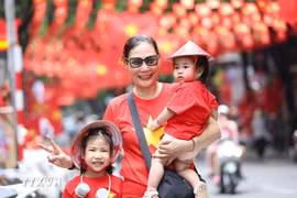 De nombreuses personnes ont immortalisé l'instant avec l'image du drapeau national sur la rue Hang Ma, dans le quartier Hoan Kiem, à Hanoï. Photo : VNA