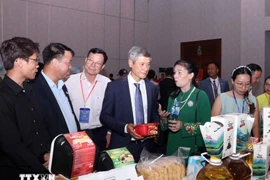 Nguyen Minh Vu, ambassadeur du Vietnam au Cambodge, et des entreprises cambodgiennes visitent le stand vietnamien. Photo : VNA