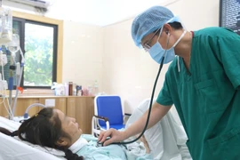 Un médecin vérifie l'état de santé de la patiente après la greffe. Photo : VietnamPlus