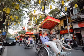 Des touristes étrangers utilisent des cyclos pour admirer la beauté antique du Vieux quartier de Hanoï. Photo : VNA