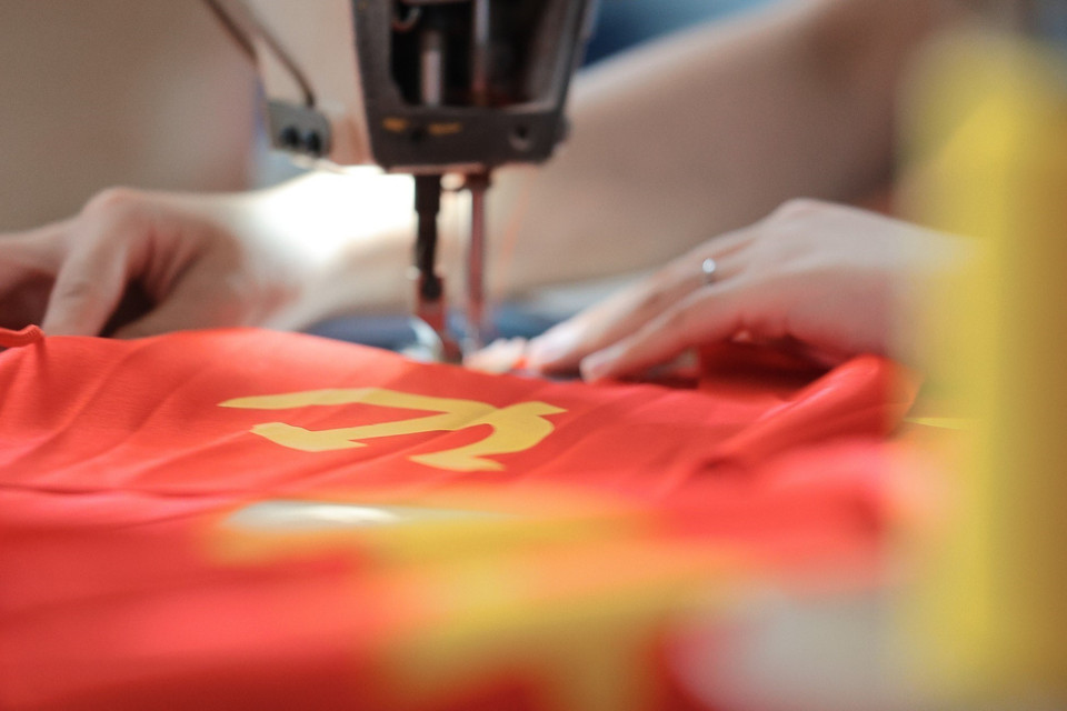 Les machines à coudre le drapeau national et le drapeau du Parti tournent à plein régime. Photo : Khanh Hoa - VNA