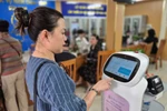 Les gens font l'expérience de robots IA appliquant la technologie de l'intelligence artificielle pour soutenir les procédures administratives dans le quartier de Cua Nam, dans la ville de Hanoi. Photo : VNA