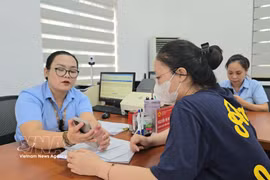 Des fonctionnaires du quartier de Mao Khe guident une citoyenne dans le dépôt en ligne de ses dossiers de certification sur le Portail national de la fonction publique. Photo : TTXVN