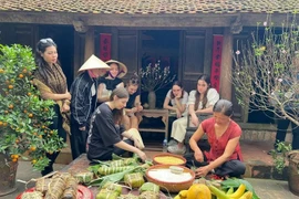 Des touristes étrangers essaient de confectionner des "banh chung" à l'ancien village de Duong Lam. Photo: VNA