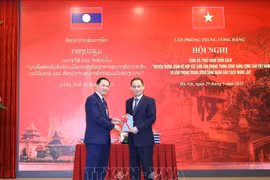 Le Hoai Trung (droite), secrétaire du Comité central du PCV et chef du Bureau du Comité central du PCV, offre un exemplaire du livre à Thongsalith Mangnomek, secrétaire du Comité central du PPRL et chef du Bureau du Comité central du PPRL. Photo : VNA