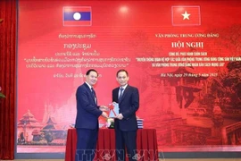 Le Hoai Trung (droite), secrétaire du Comité central du PCV et chef du Bureau du Comité central du PCV, offre un exemplaire du livre à Thongsalith Mangnomek, secrétaire du Comité central du PPRL et chef du Bureau du Comité central du PPRL. Photo : VNA