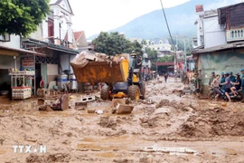 Des excavatrices aident à ramasser la boue, les branches d'arbres et les déchets emportés par les récentes inondations dans la commune de Song Ma, province de Son La. Photo : VNA