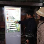 Des touristes utilisent un kiosque interactif au temple öng Hoàng Muoi dans la province de Nghe An. Photo: VNA