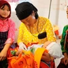 Une sage-femme prend un bébé dans ses bras sous le regard attentif de sa mère. Photo: VNA
