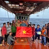 Les forces de l'ordre maritimes de Hô Chi Minh-Ville offrent un drapeau national et diffusé des informations sur la pêche INN aux pêcheurs. Photo: VNA