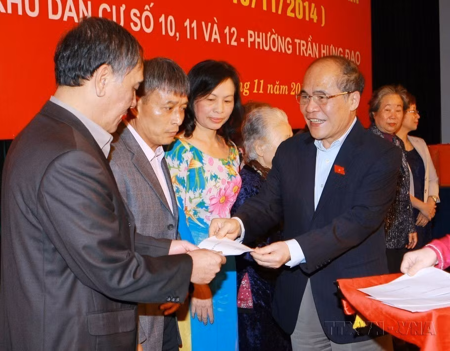 Le président de l'Assemblée nationale, Nguyen Sinh Hung, offre des cadeaux aux familles culturelles exemplaires lors de la Fête de grande union nationale entre les zones résidentielles n° 10, 11 et 12, quartier de Tran Hung Dao, à Hanoï (2014). Photo : VNA