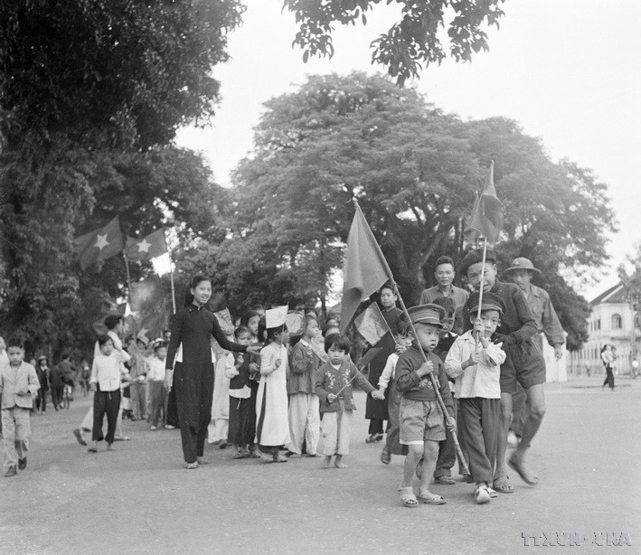 Les enfants de Hanoï et leurs proches portèrent des drapeaux pour accueillir les soldats qui revinrent libérer la capitale. Photo : archives-VNA