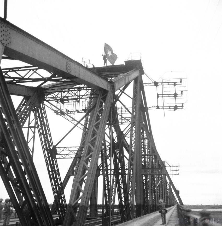 Les soldats plantèrent le drapeau national sur le toit du pont Long Bien. Photo : Archives-VNA