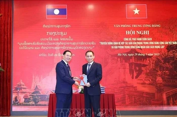 Le Hoai Trung (droite), secrétaire du Comité central du PCV et chef du Bureau du Comité central du PCV, offre un exemplaire du livre à Thongsalith Mangnomek, secrétaire du Comité central du PPRL et chef du Bureau du Comité central du PPRL. Photo : VNA