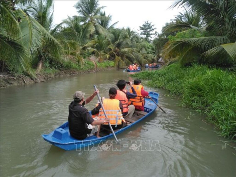 Des touristes font l'expérience du canoë sur la rivière à la ferme touristique de chèvres de Dong Nghi, à Tiên Giang. Photo: VNA