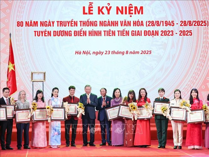 Le secrétaire général Tô Lâm et le ministre de la Culture, des Sports et du Tourisme Nguyên Van Hùng remettent des certificats de mérite et des fleurs pour féliciter les figures exemplaires du secteur culturel. Photo : VNA