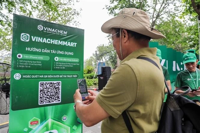 Les gens scannent directement le code QR de la plateforme de commerce électronique VinachemMart dans la rue piétonne du lac Hoàn Kiêm. Photo: VNA