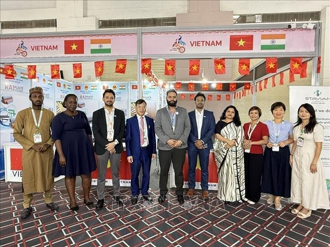 Le conseiller commercial Bùi Trung Thuong (4e de gauche à droite) et des invités nationaux et étrangers visitant le stand. Photo: VNA
