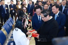 Le Premier ministre Pham Minh Chinh remet des enveloppes rouges symboliques du Têt aux voyageurs et au personnel ferroviaire, à la Gare de Hanoi, le lundi 27 janvier. Photo : VNA