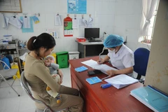 Le personnel médical examine et vérifie l'état de santé de l'enfant avant la vaccination. Photo: VNA
