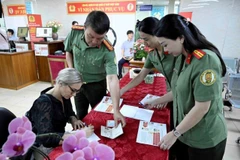 Des agents du Département de l’immigration aident une ressortissante étrangère à Hanoi à remplir les formulaires pour les comptes d’identification électronique de niveau 2 avec VneID, le 1er juillet. Photo : VNA
