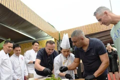 Des touristes internationaux découvrent la préparation de salades de poisson au Festival gastronomique de Dà Nang 2025. Photo: NDEL