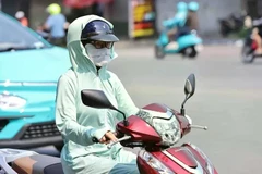 Une motocycliste se couvre le visage d’un tissu pour s’abriter de la chaleur. Photo : VNA