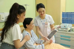 Le personnel médical de l'hôpital de l'Université de médecine et de pharmacie d'Ho Chi Minh-Ville utilise des tablettes pour mettre à jour et partager des informations avec une patiente. Photo : VNA