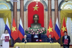 Le président de l’époque, Tô Lâm (assis, à droite) et le président russe Vladimir Poutine supervisent l'échange de documents signés entre les deux pays à l’issue de leur entretien, à Hanoi, le 20 juin 2024. Photo : VNA
