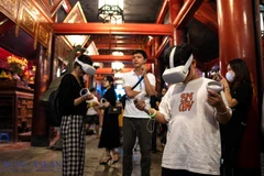 Les touristes découvrent l'écriture calligraphique grâce à la technologie de réalité virtuelle au Temple de la Littérature. Photo : mekongasean.vn